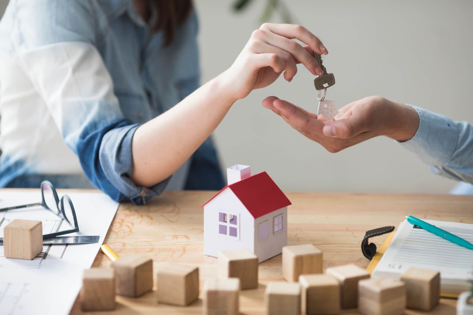 photologuephotos2023-07primer-plano-mano-mujer-que-da-llave-casa-al-hombre-sobre-mesa-madera_1_1jpg